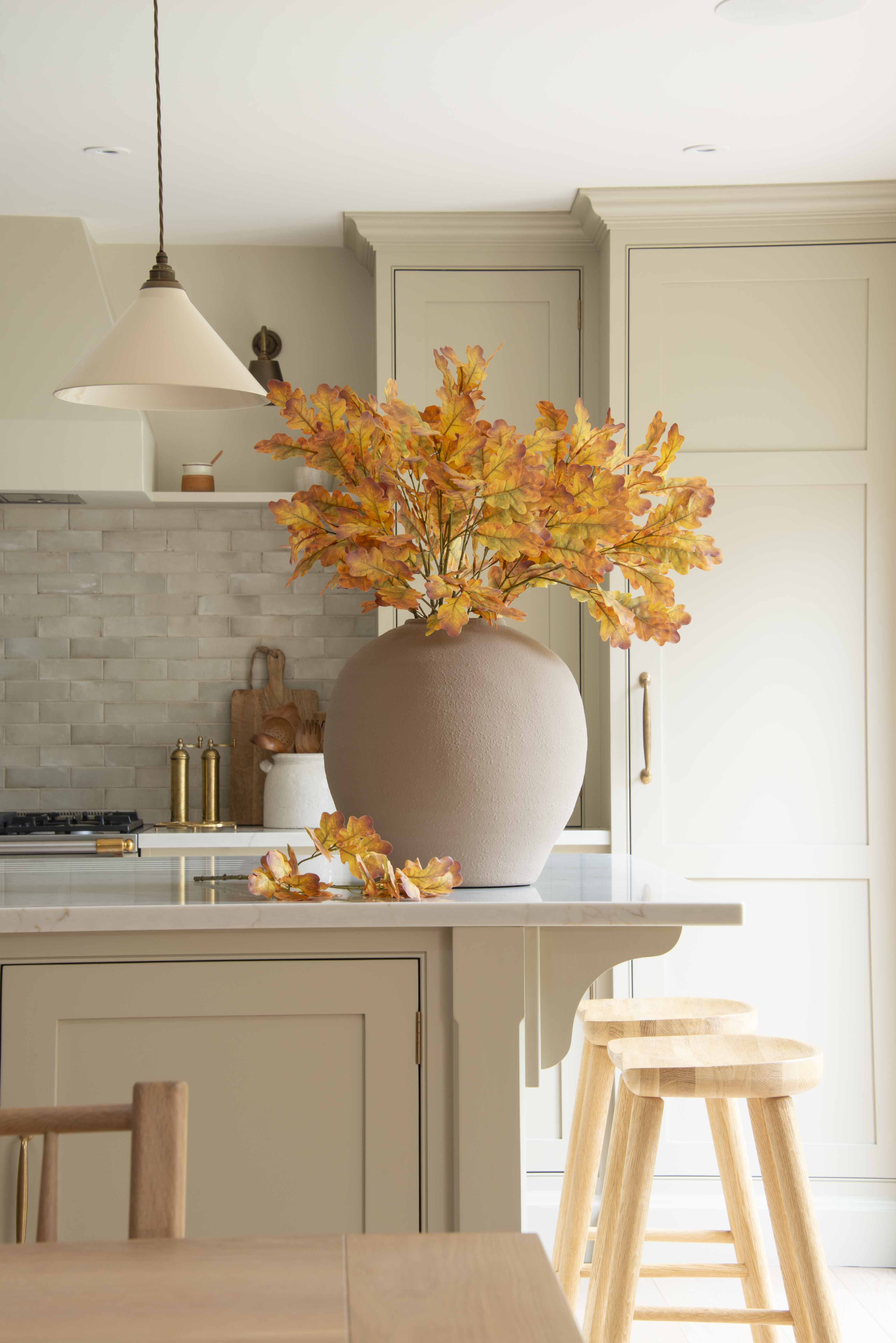 A large round beige vase filled with autumn florals
