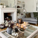 This coffee table is crafted from acacia wood with a rattan and glass top. Candles and flowers sit on top.