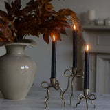 Decorative candle holders with lit candles next to a vase on a marble surface.