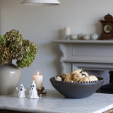Decorative setup on a marble surface with a candle, bowl, and small figures.