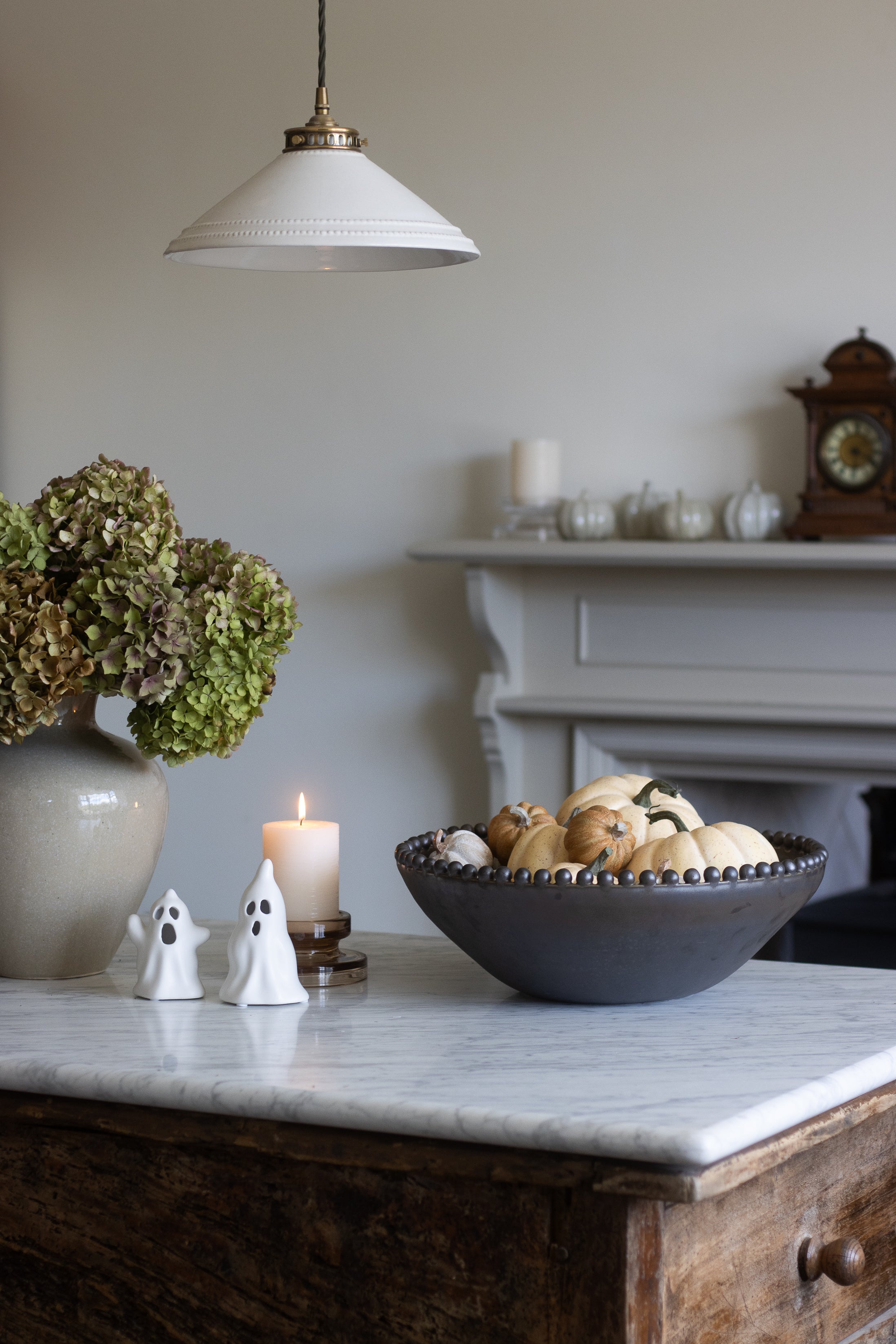 Decorative setup on a marble surface with a candle, bowl, and small figures.