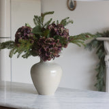 White vase with flowers on a marble countertop