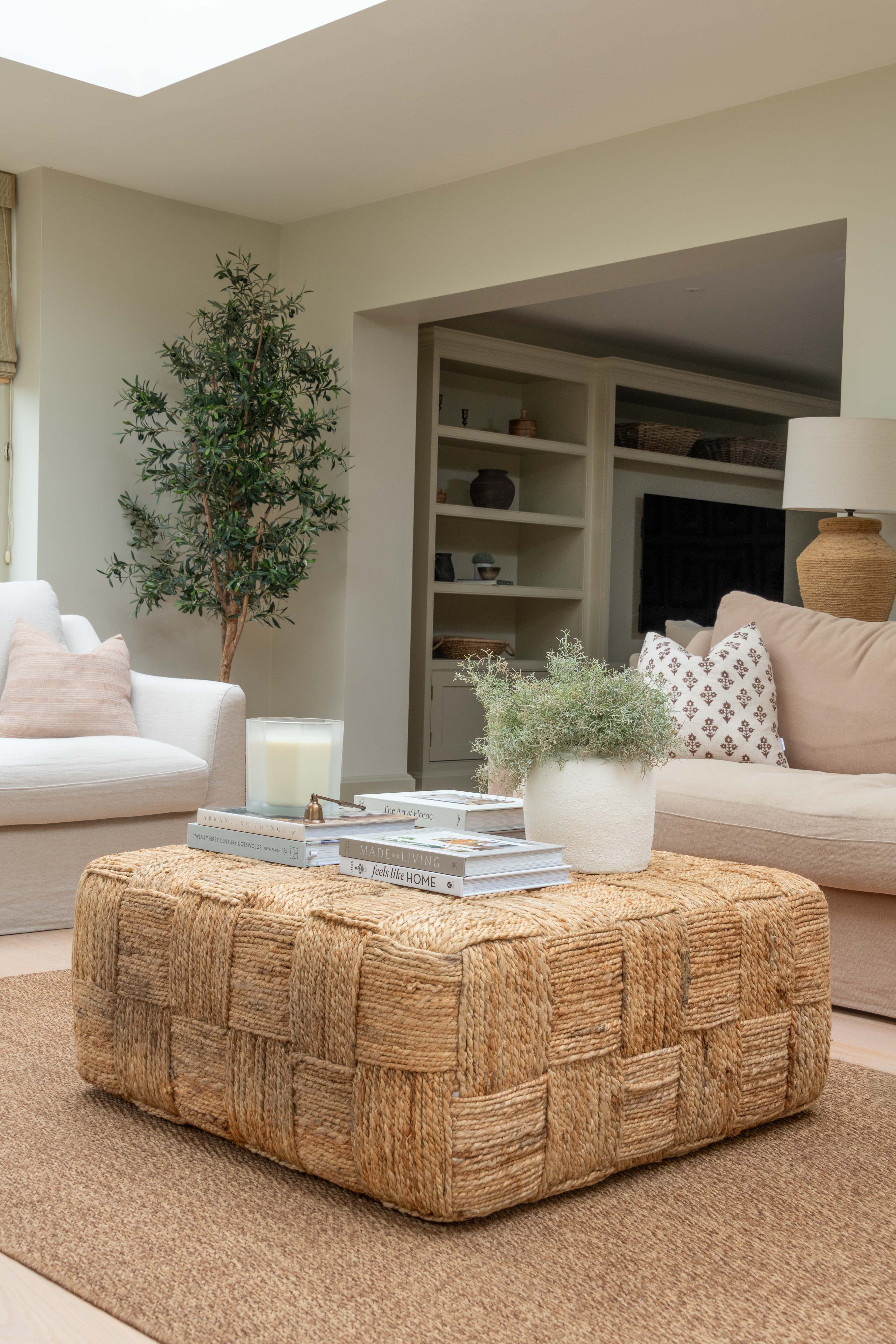 Living room with a woven ottoman, books, and a candle.