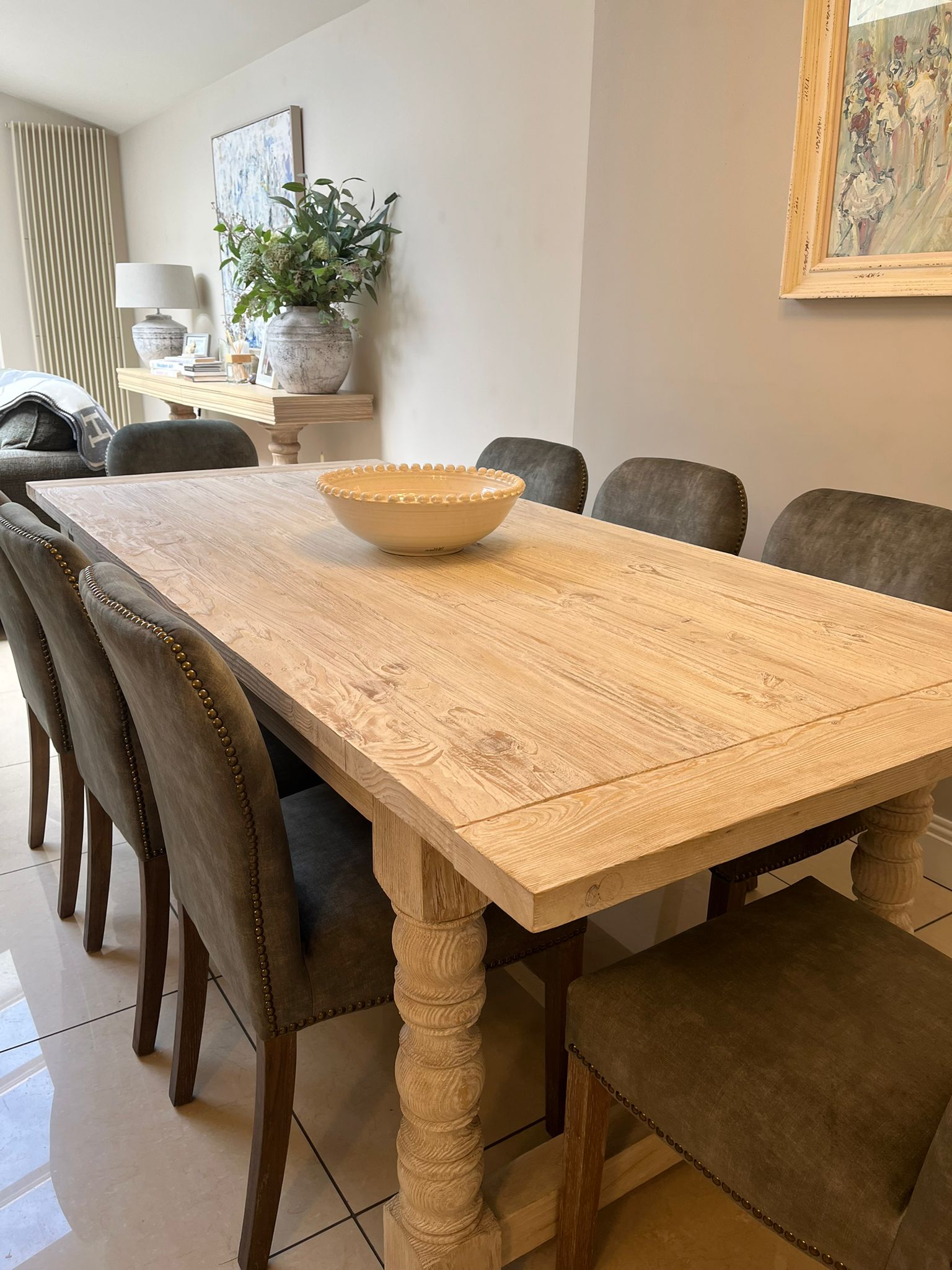 Wooden dining table with chairs in a room with decor elements.