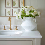Introduce timeless elegance to your space with the “Arlo” White Ceramic Vase, a beautifully crafted piece that blends form and function. Featuring a striking geometric silhouette and distinctive double side handles, this modern ceramic vase makes a bold statement while maintaining a clean, minimalist aesthetic. Its matte white finish and sculptural shape make it an ideal accent for bathroom vanities, entryway consoles, or styled shelves. Perfect for lovers of modern, coastal, or farmhouse décor, the Arlo va