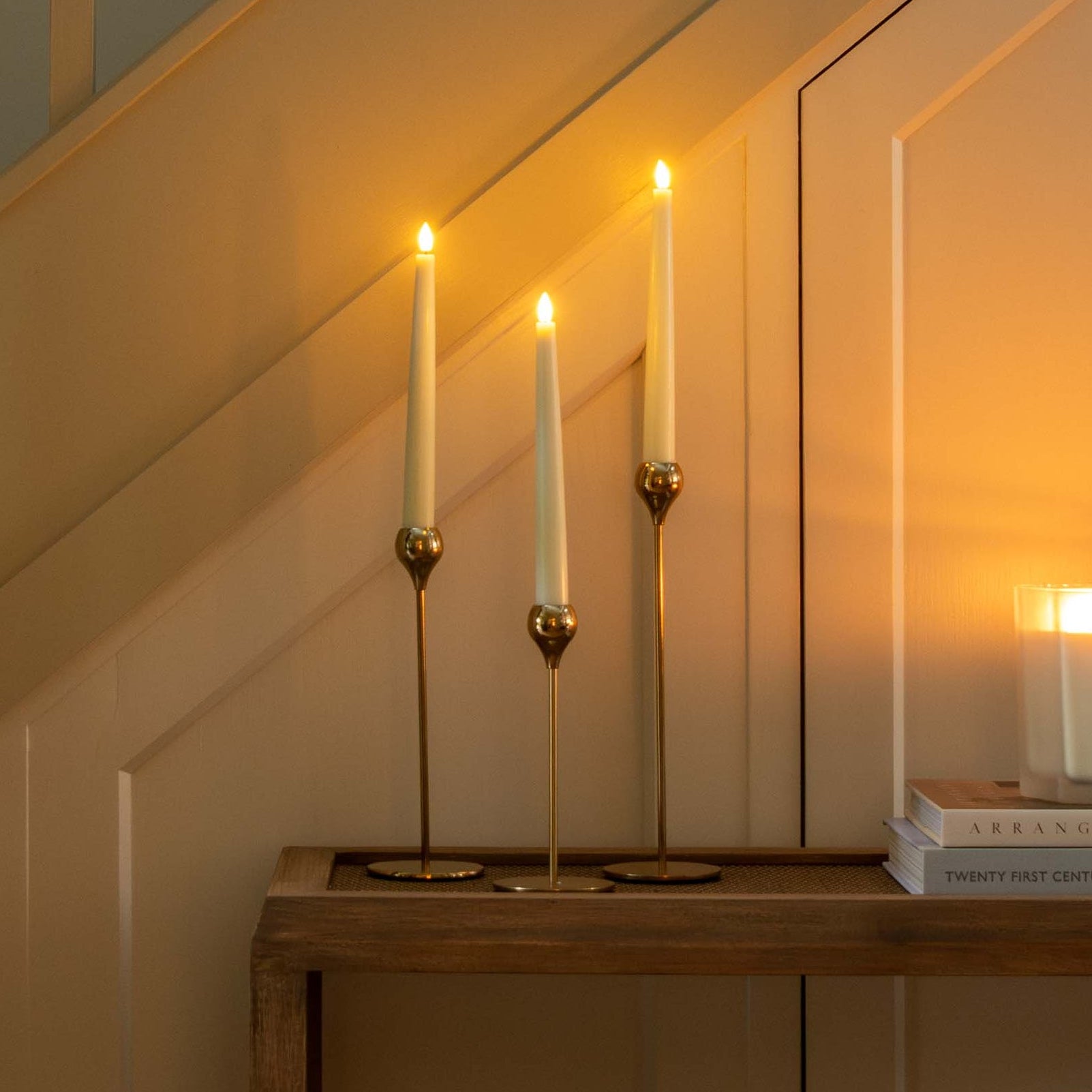 Decorative staircase with greenery, candles, and pinecones in a warm indoor setting.