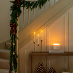Decorative staircase with greenery, candles, and decorative items in a warm indoor setting.