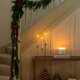 Decorative staircase with greenery, candles, and decorative items in a warm indoor setting.