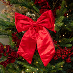 Decorative red bow on a Christmas tree with lights and ornaments.