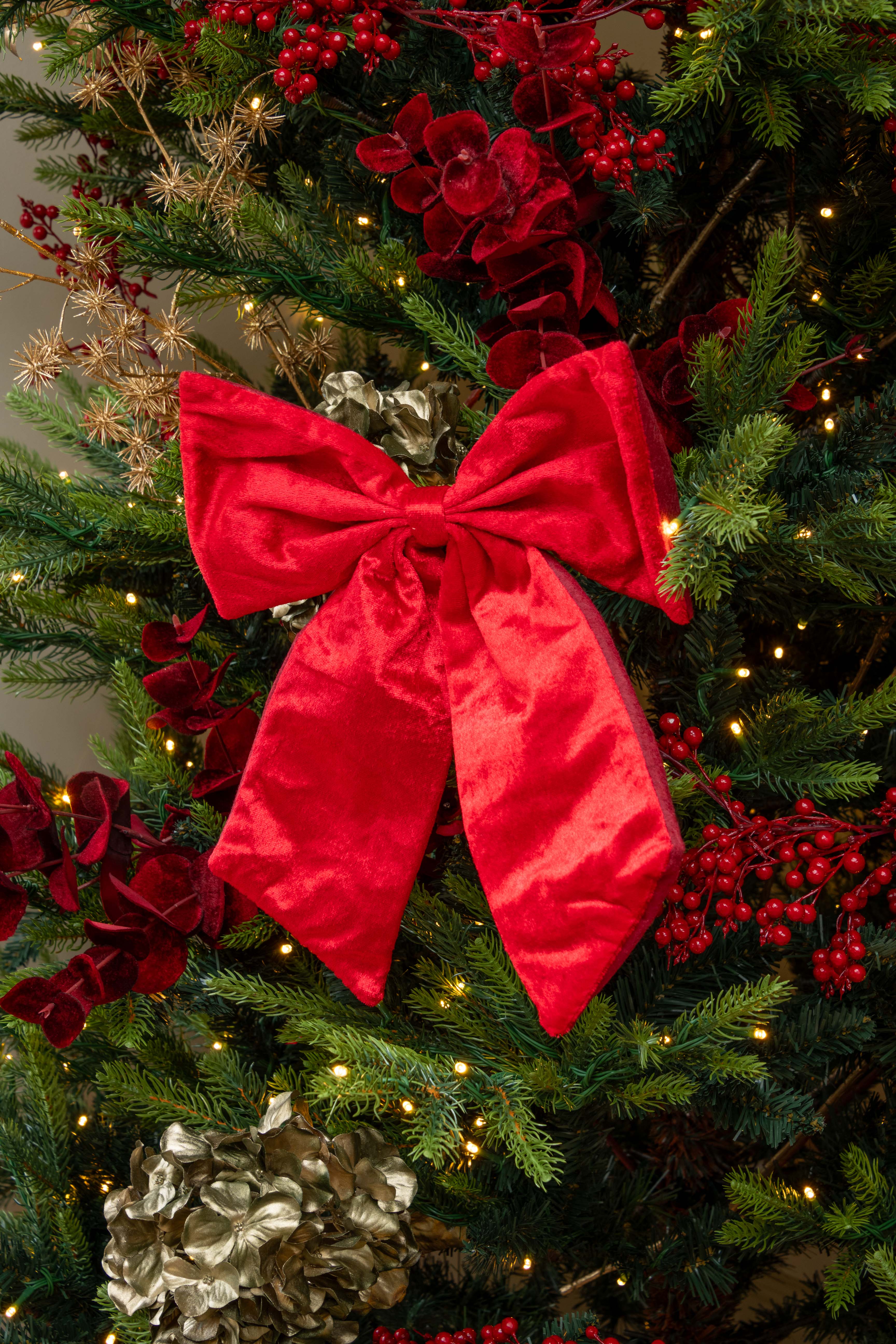 Decorative red bow on a Christmas tree with lights and ornaments.