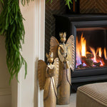 Decorated fireplace with greenery and a candle, framed artwork above, and a cozy living room setting.