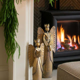 Decorated fireplace with greenery and a candle, framed artwork above, and a cozy living room setting.