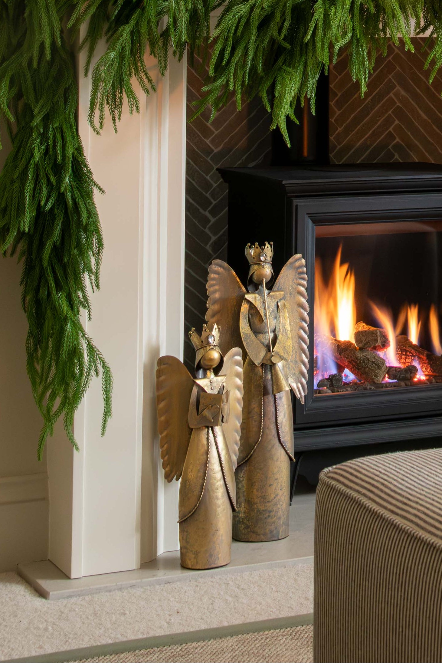 Decorated fireplace with greenery and a candle, framed artwork above, and a cozy living room setting.