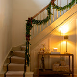 Decorative staircase with garland, lights, and a small table with a deer figurine.