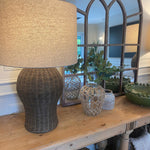 Large rattan lamp with linen shade mirrorsitting on a console table next to a