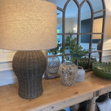 Large rattan lamp with linen shade mirrorsitting on a console table next to a