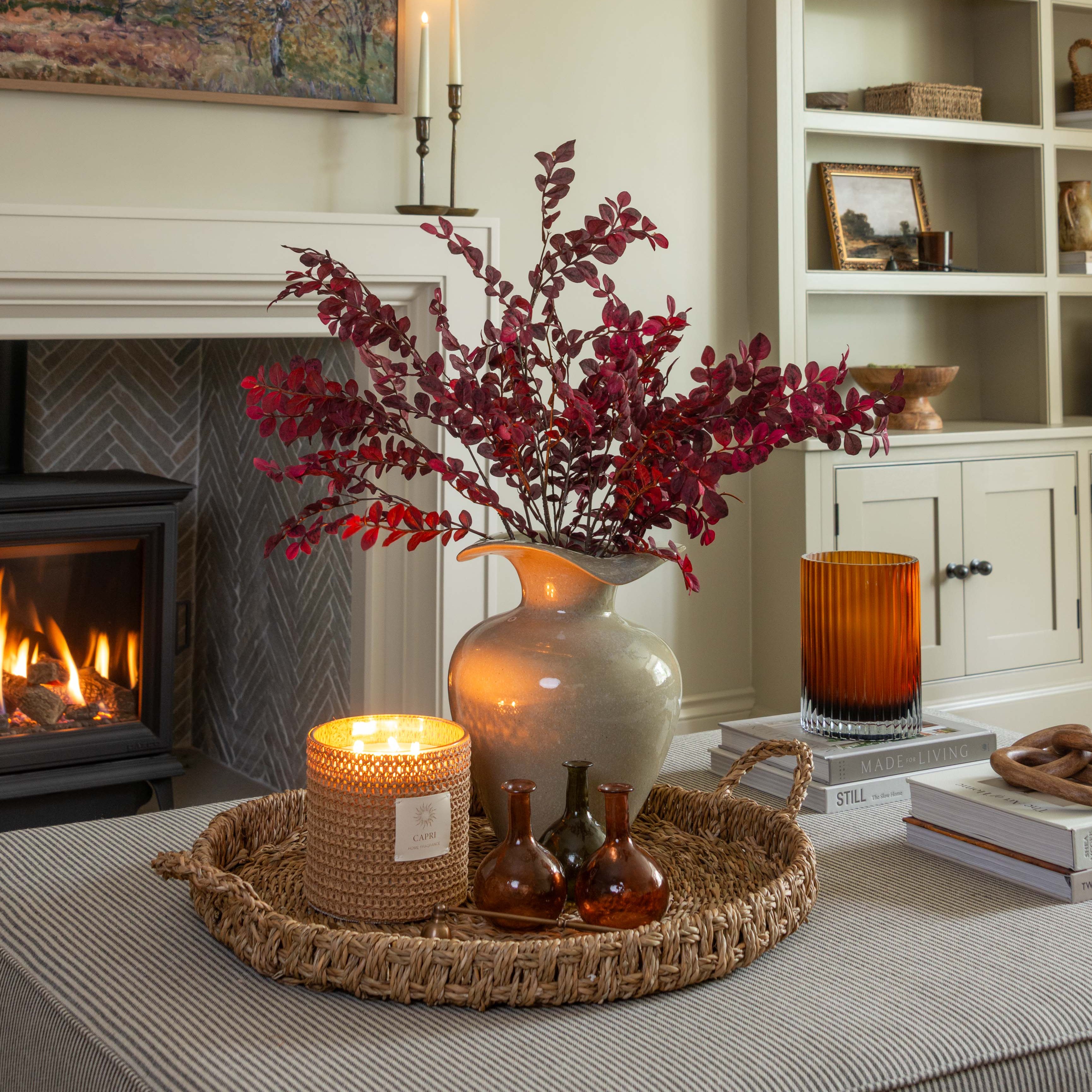 Decorative setup with candles, flowers, and a vase on a table in a living room.
