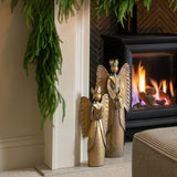 Decorated fireplace with greenery and a candle, framed artwork above, and a cozy living room setting.