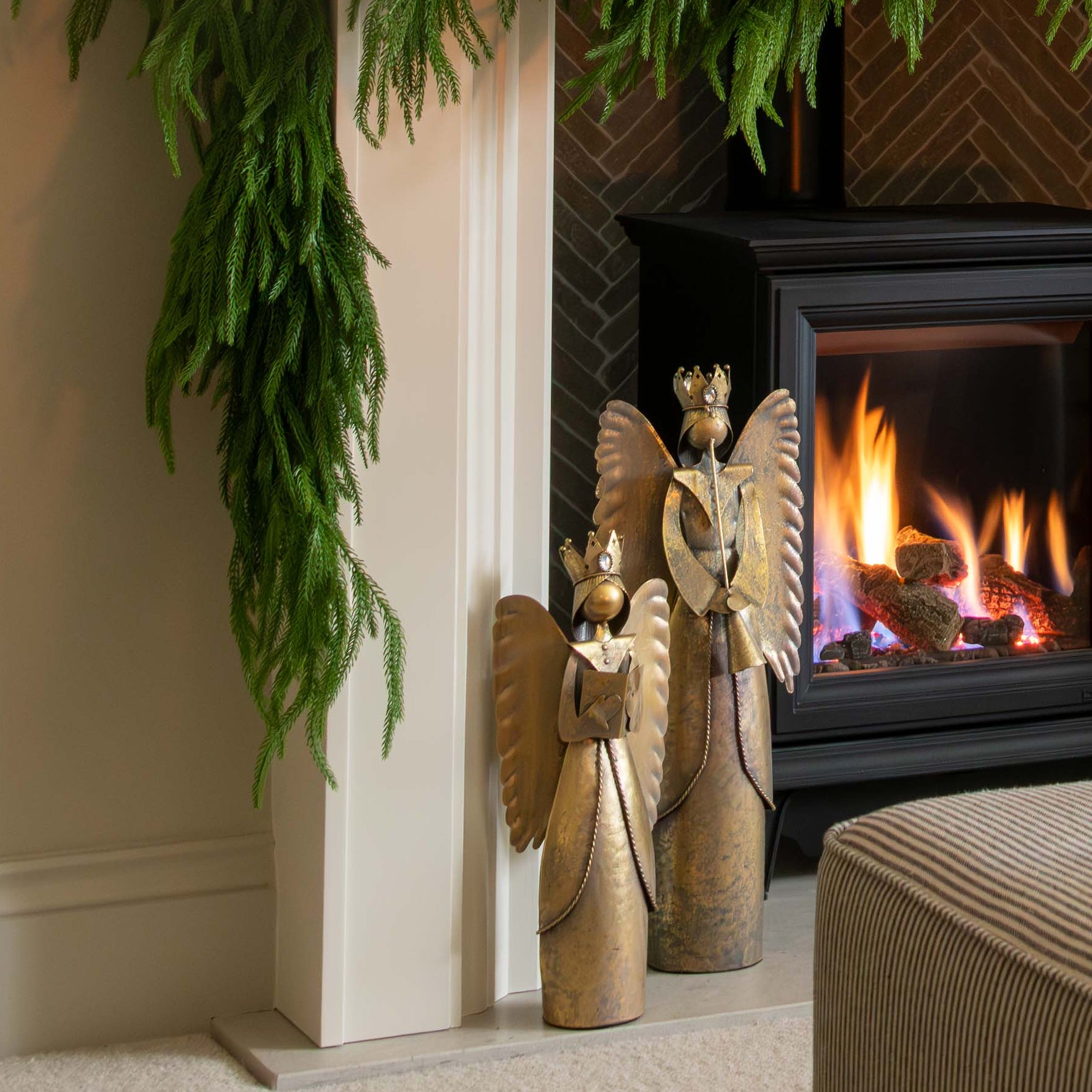 Decorated fireplace with greenery and a candle, framed artwork above, and a cozy living room setting.