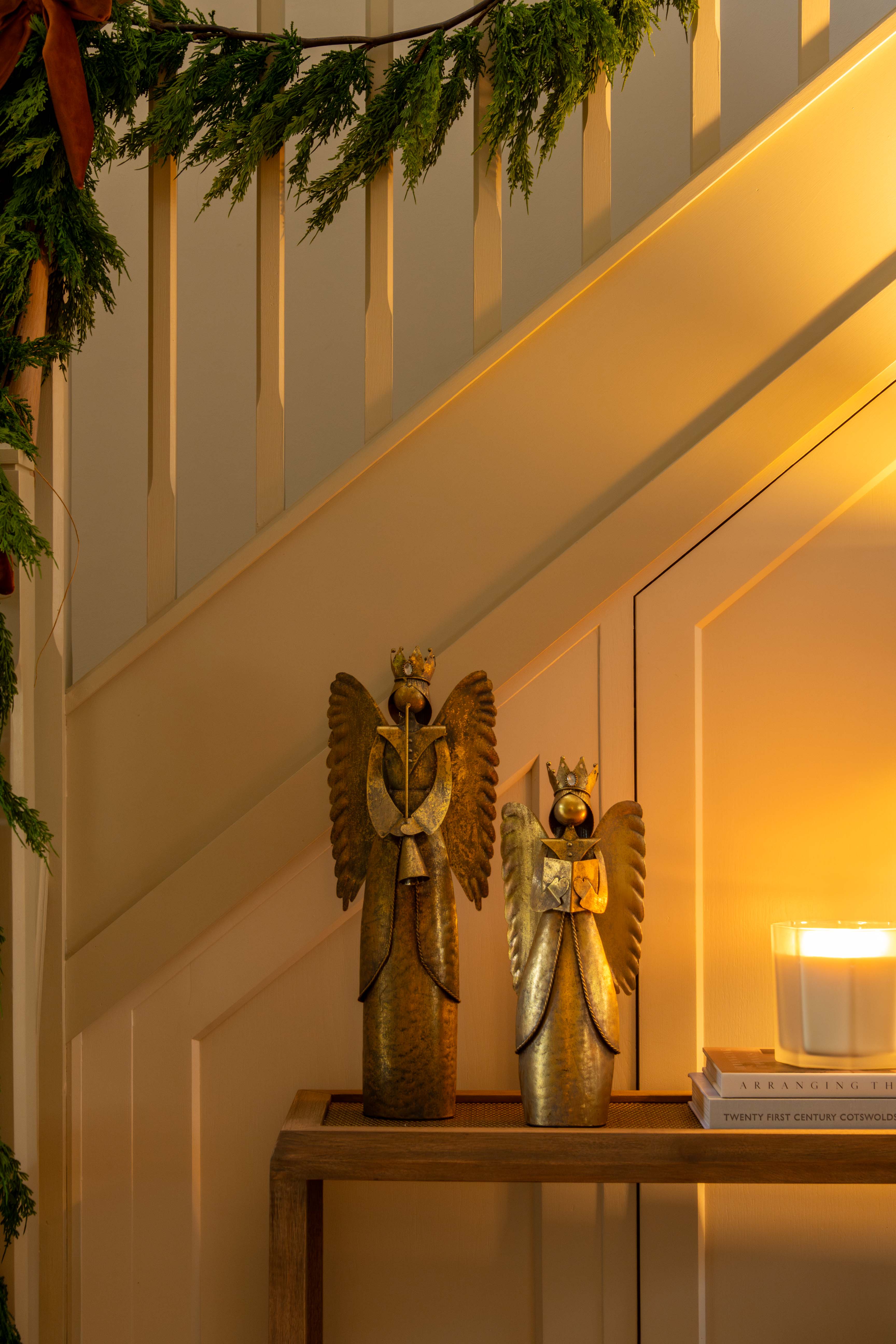 Decorative angel figurines on a table with a candle and mirror in a warm indoor setting.