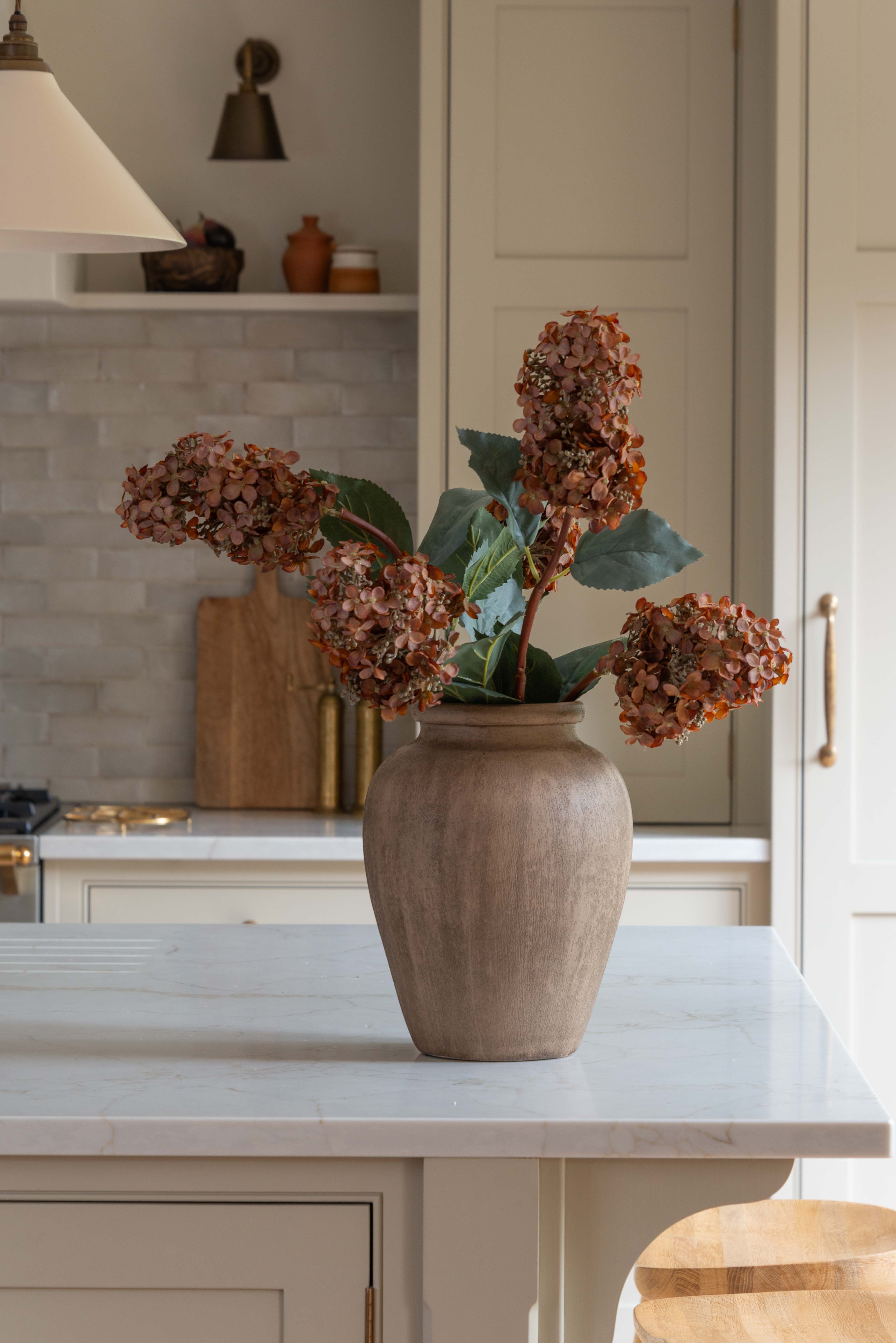 Brown Tall Hydrangea Stem in a rustic vase on a kitchen island