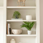 A decorative faux green fern planted in a stone pot.