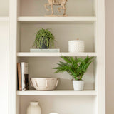 A decorative faux green fern planted in a stone pot.