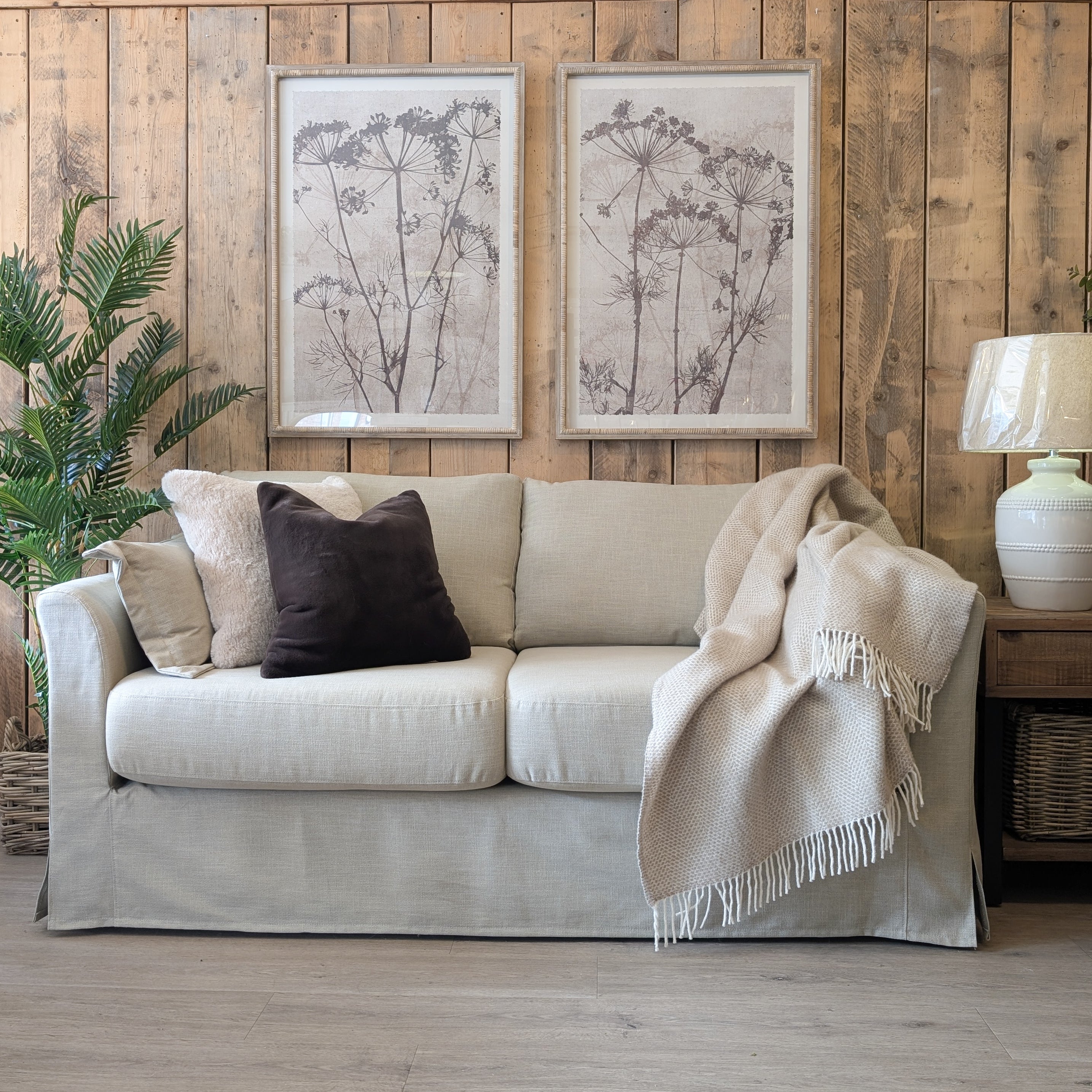 Carmel neutral loose cover sofa in Keystone Earth fabric with plush cushions, soft throw, and rustic wood backdrop