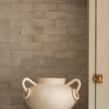 Beige ceramic pot on a kitchen counter with a tiled backsplash