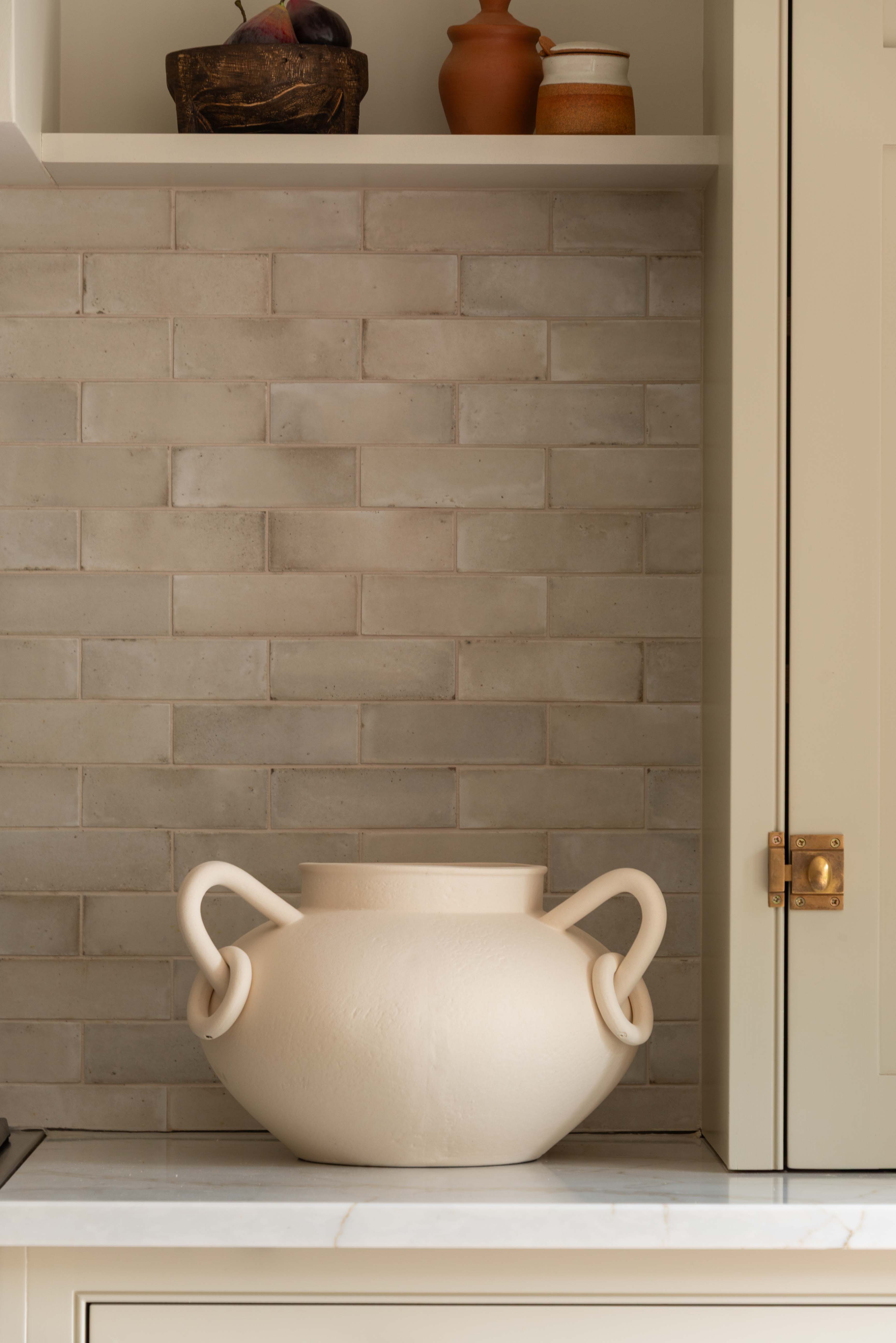Beige ceramic pot on a kitchen counter with a tiled backsplash