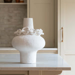 White sculptural porcelain vase with decorative ceramic chain accent around the neck, modern minimalist design