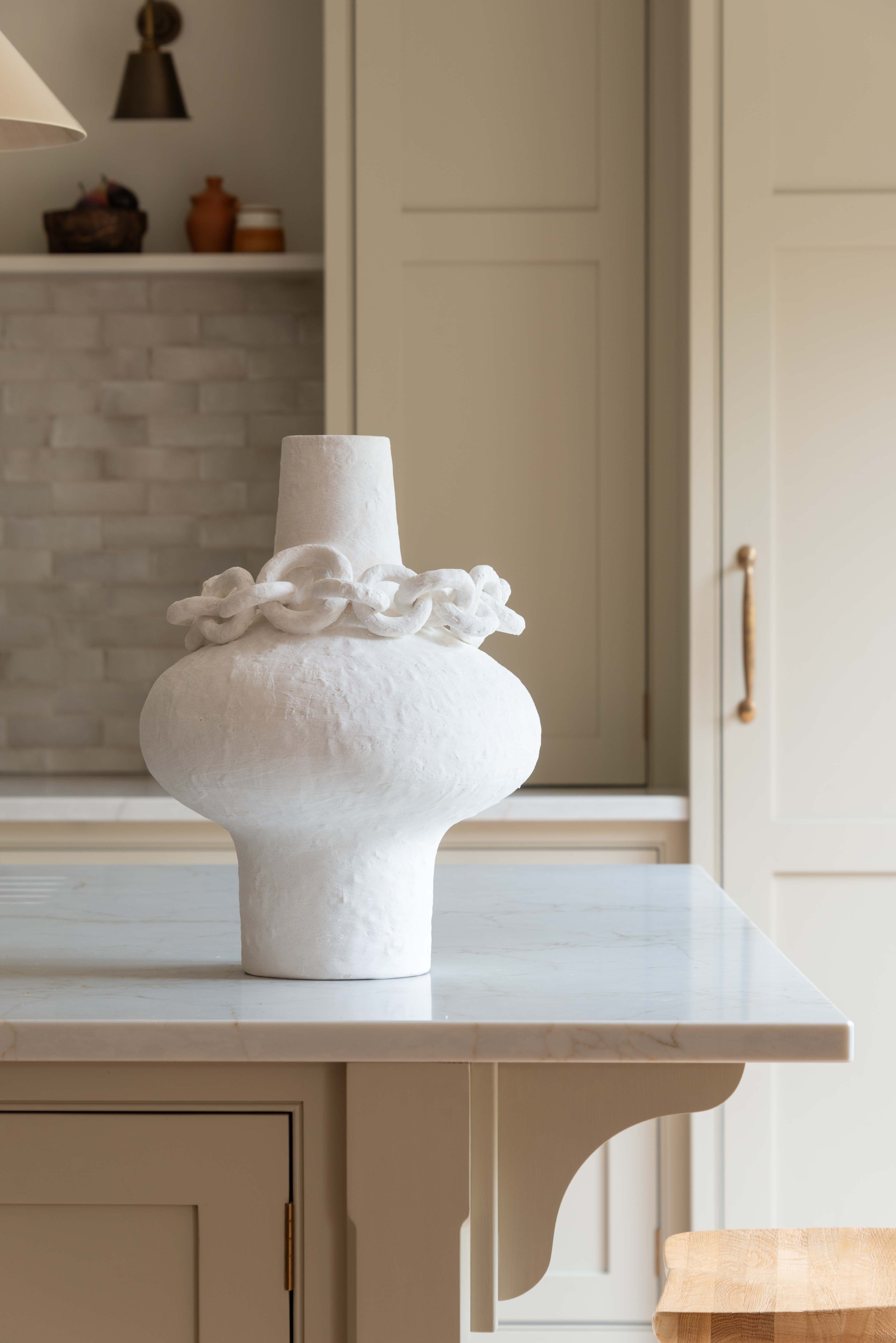 White sculptural porcelain vase with decorative ceramic chain accent around the neck, modern minimalist design