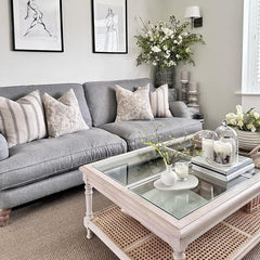 Tastefully decorated living room with a coffee table crafted from acacia wood with a rattan and glass top.