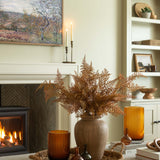 Living room with fireplace, vase of dried ferns, and decorative items.