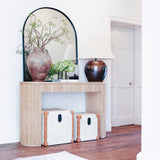 Arch-shaped mirror with black trim sitting on a console table.