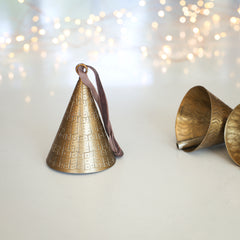 Charles Ted Artisan Brass Bell Baubles with hand-hammered patterns and velvet ties displayed on a white surface and styled with soft lights