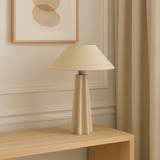 Beige lamp on a wooden side table with abstract art on the wall
