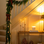 Decorative staircase with Christmas garland, candles, and decorative items.