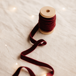 Spool of red ribbon on a textured surface with blurred lights in the background