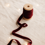 Spool of red ribbon on a textured surface with blurred lights in the background