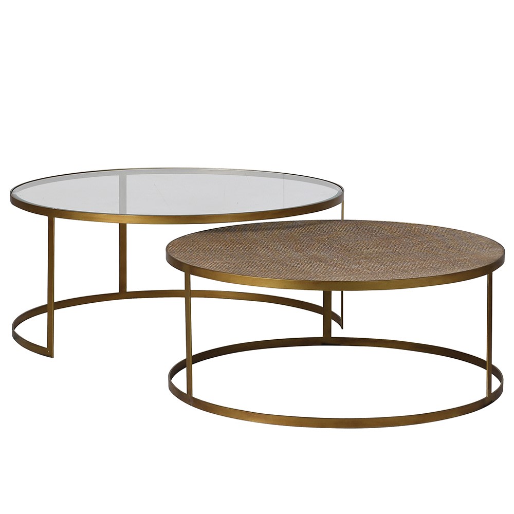 Two nesting coffee tables with gold-colored legs and a glass top on the larger table, and a rattan top on the smaller table.