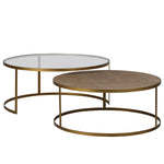 Two nesting coffee tables with gold-colored legs and a glass top on the larger table, and a rattan top on the smaller table.