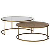 Two nesting coffee tables with gold-colored legs and a glass top on the larger table, and a rattan top on the smaller table.