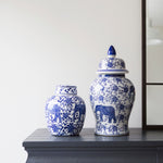 Two blue and white ceramic jars with elephant designs on a wooden surface.