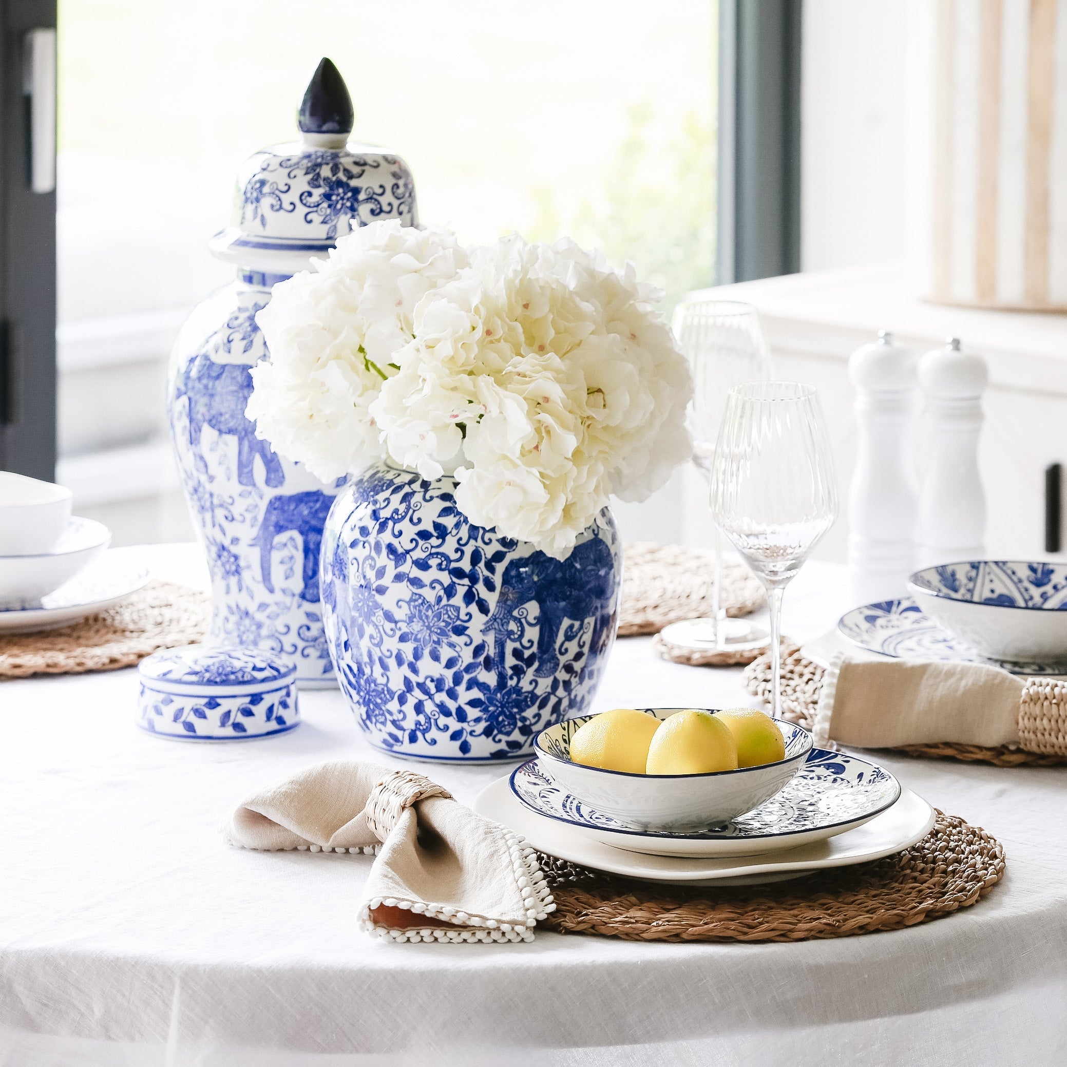 Table setting with blue and white ceramic vases, flowers, and plates.