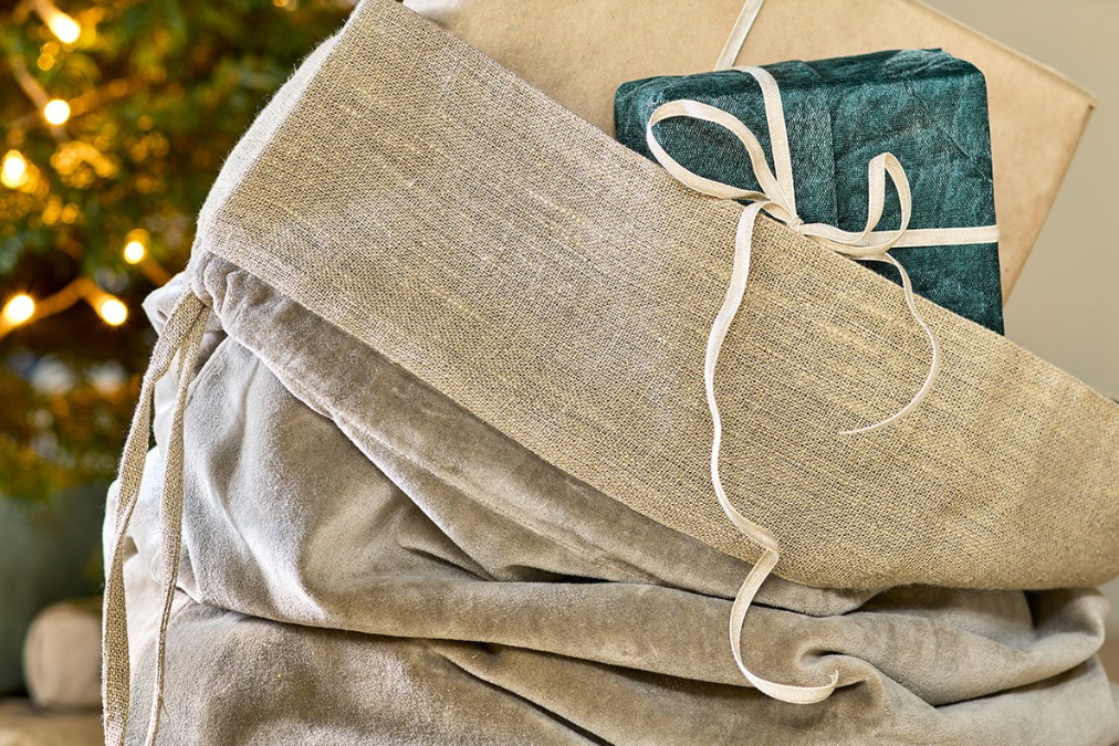Gift sack made with grey velvet and rustic linen, stuffed with wrapped gifts close up
