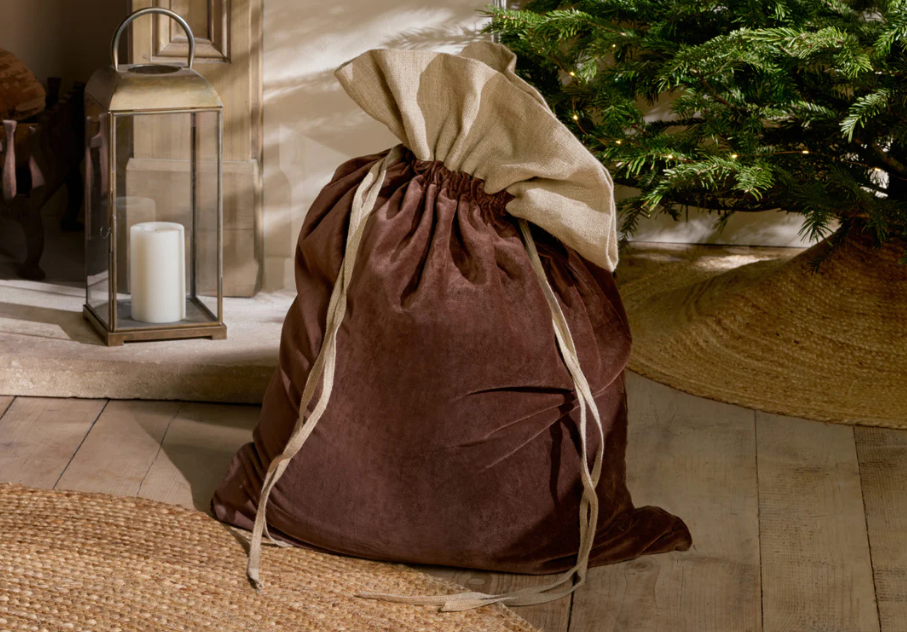 Charles Ted Cotton Velvet Christmas Sack in mocha with linen top and jute tie placed under a Christmas tree by a fireplace
