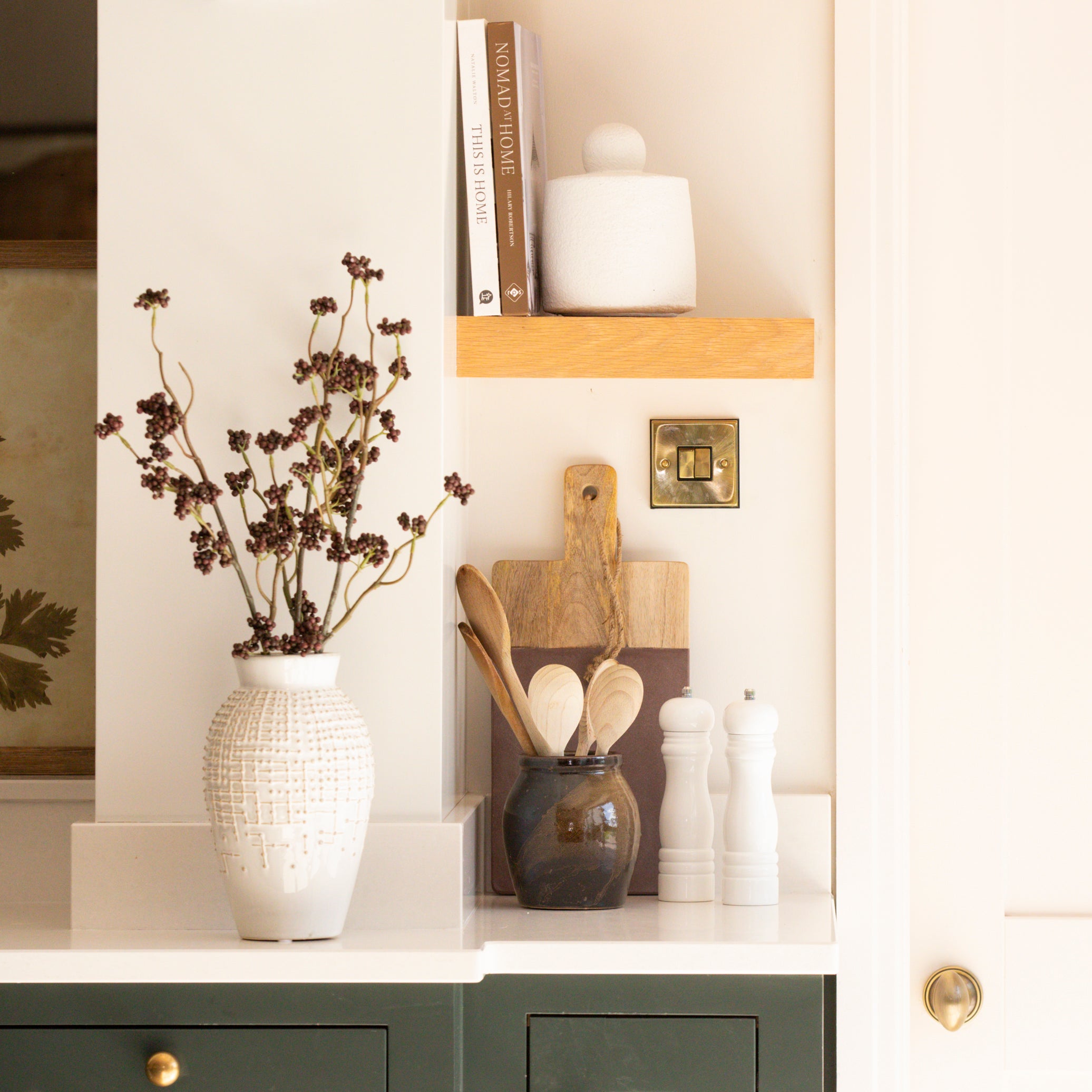 White ceramic vase with berry branches styled in a modern kitchen