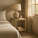 Evelyn oak end table styled beside bed with lamp and books