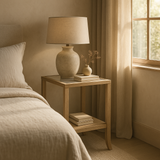Evelyn oak end table styled beside bed with lamp and books